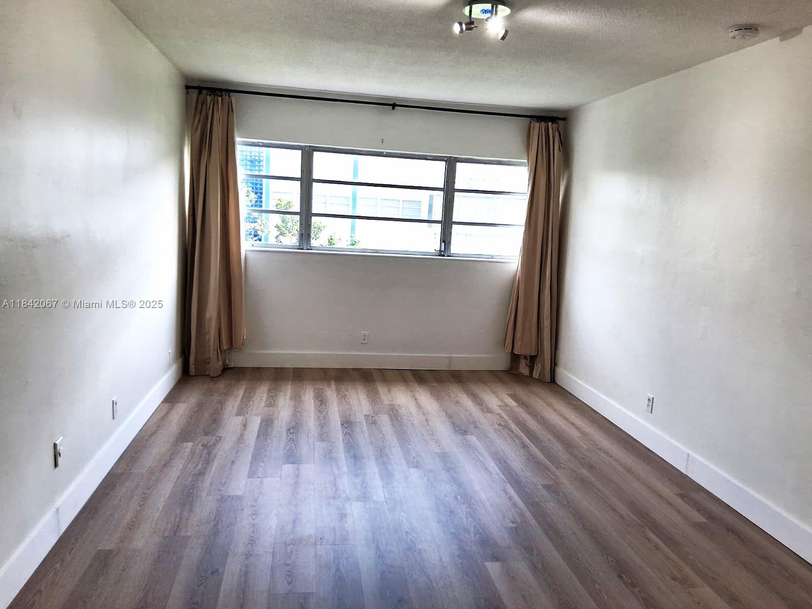 16801 Northeast 14th Avenue, Unit 209 Miami, FL 33162 - Photo 15 of 28 an empty room with wooden floor and windows