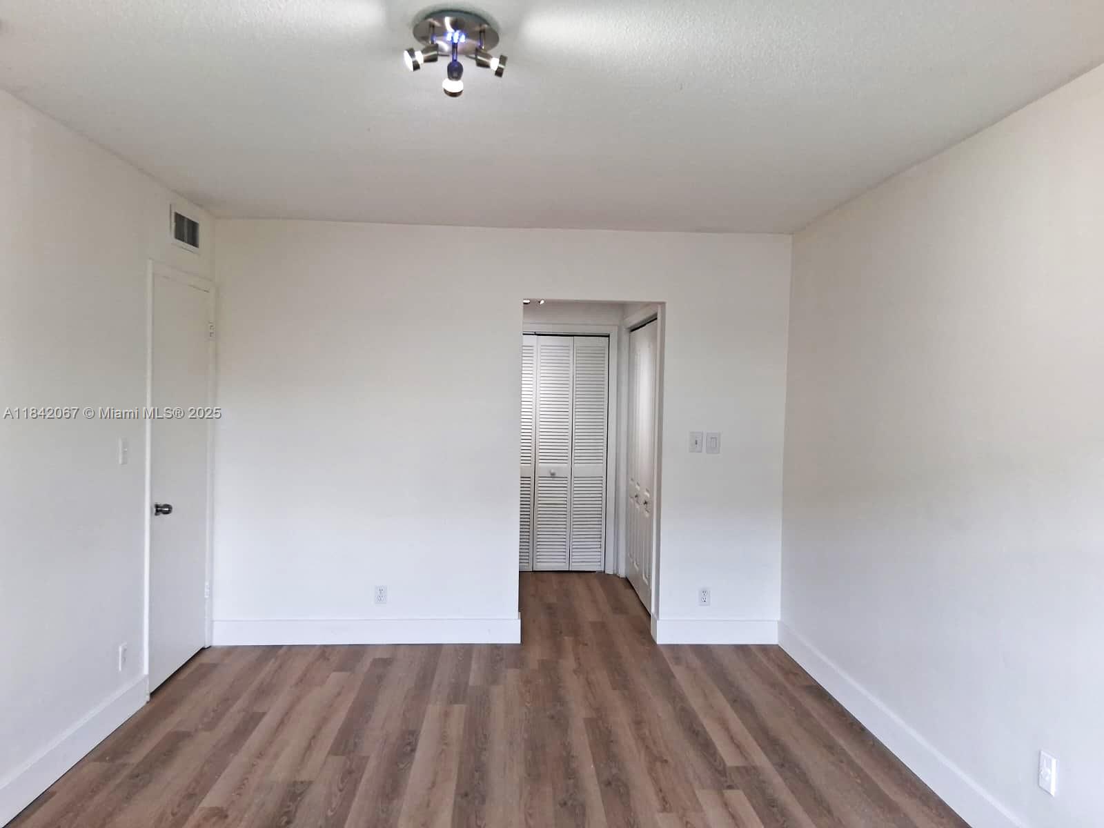 16801 Northeast 14th Avenue, Unit 209 Miami, FL 33162 - Photo 16 of 28 a view of an empty room with wooden floor