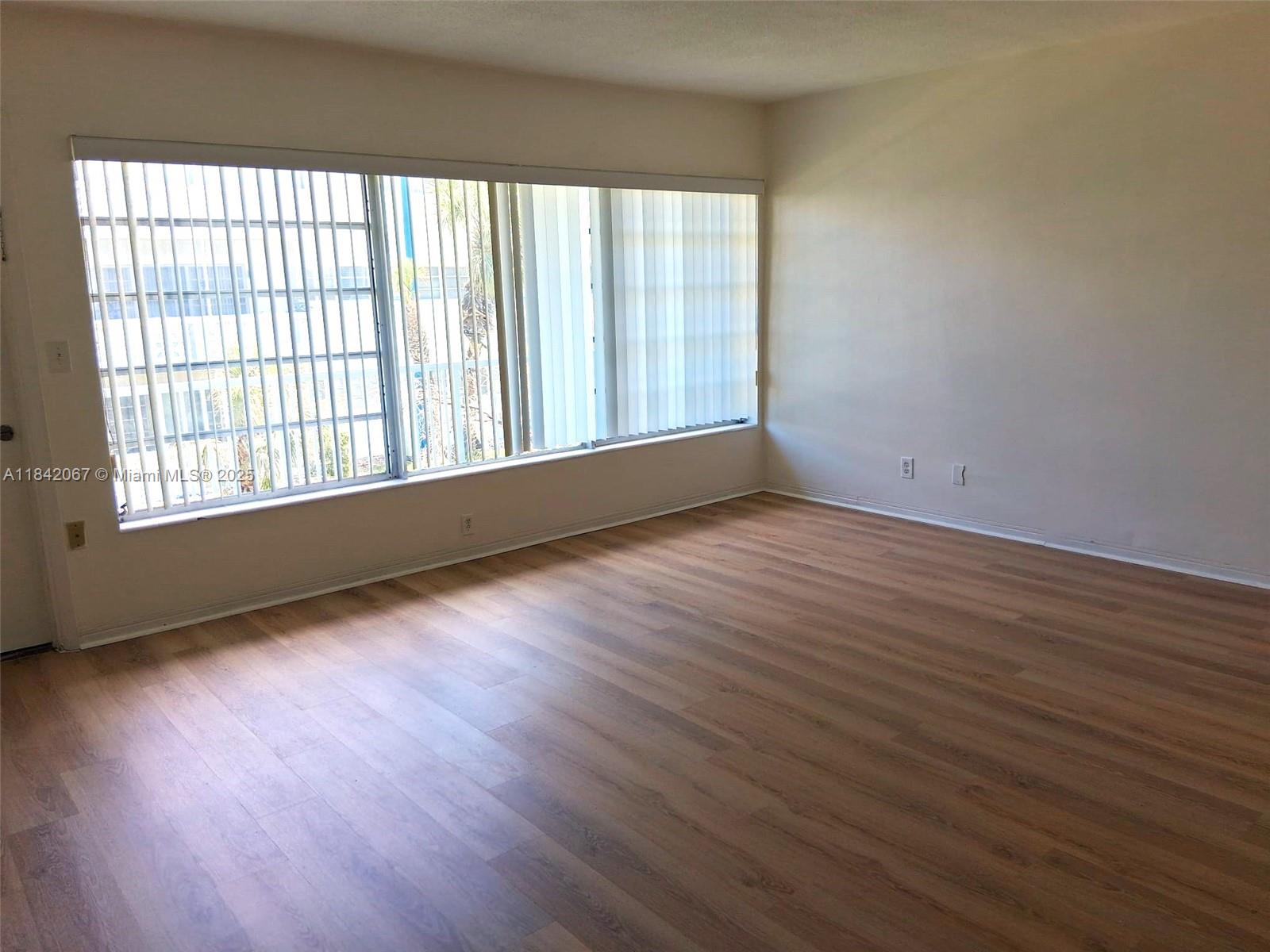 16801 Northeast 14th Avenue, Unit 209 Miami, FL 33162 - Photo 5 of 28 a view of an empty room with wooden floor and a window