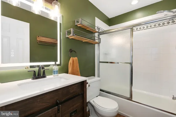 a bathroom with a sink a toilet a mirror and shower