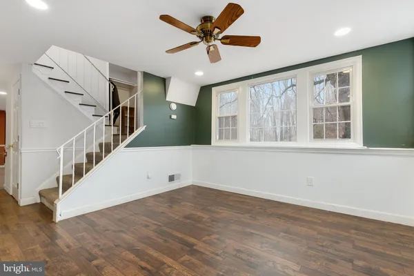 a view of an empty room with wooden floor and a ceiling fan