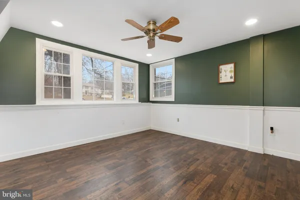 an empty room with wooden floor and ceiling fan