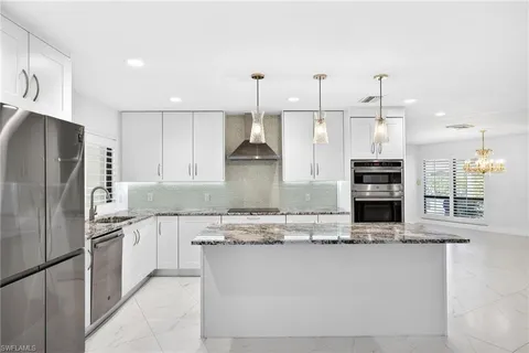 a kitchen with stainless steel appliances granite countertop a refrigerator a sink and a stove