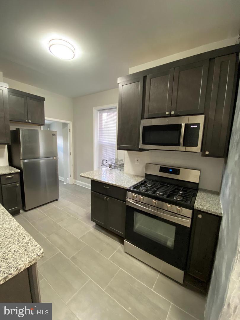 325 East 21st Street Baltimore, MD 21218 - Photo 2 of 28 a kitchen with granite countertop a refrigerator stove and microwave