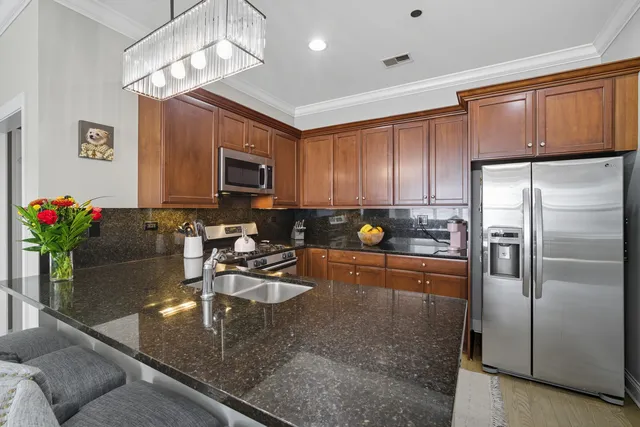 a kitchen with stainless steel appliances granite countertop a refrigerator a stove and a sink with granite countertops