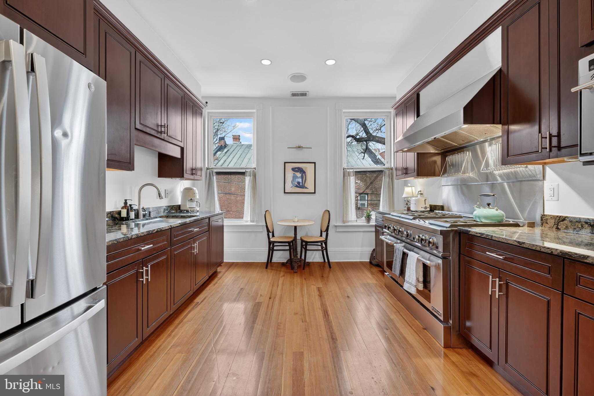 1731 Riggs Place Northwest, Unit 1 Washington, DC 20009 - Photo 14 of 20 a kitchen with stainless steel appliances granite countertop a refrigerator a sink dishwasher a stove and white countertops with wooden floor