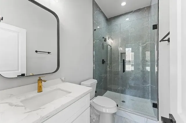 a bathroom with a granite countertop sink toilet and shower