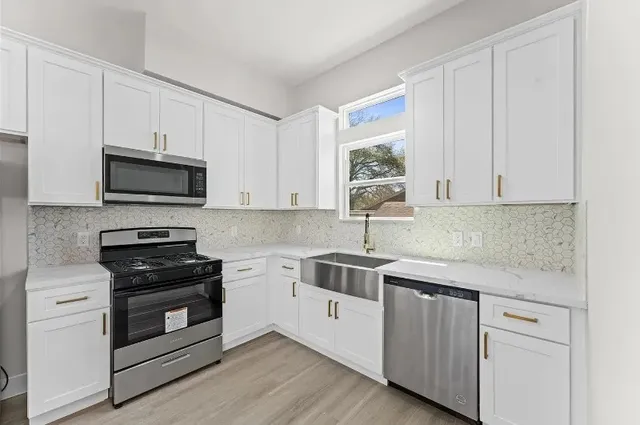 a kitchen with white cabinets stainless steel appliances and sink