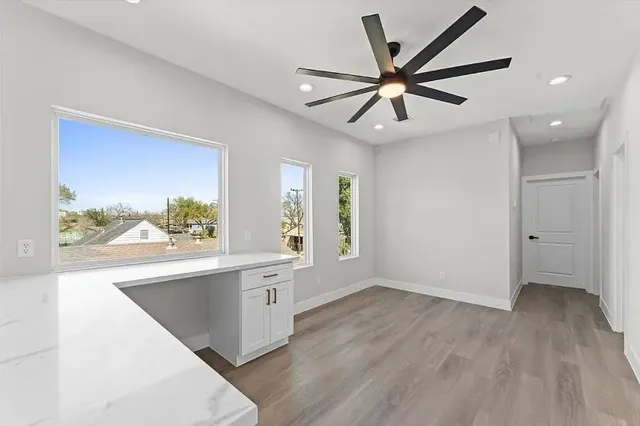 a view of a big room with wooden floor a ceiling fan and windows