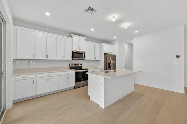 a kitchen with white cabinets and stainless steel appliances
