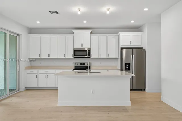 a kitchen with kitchen island a white cabinets and refrigerator