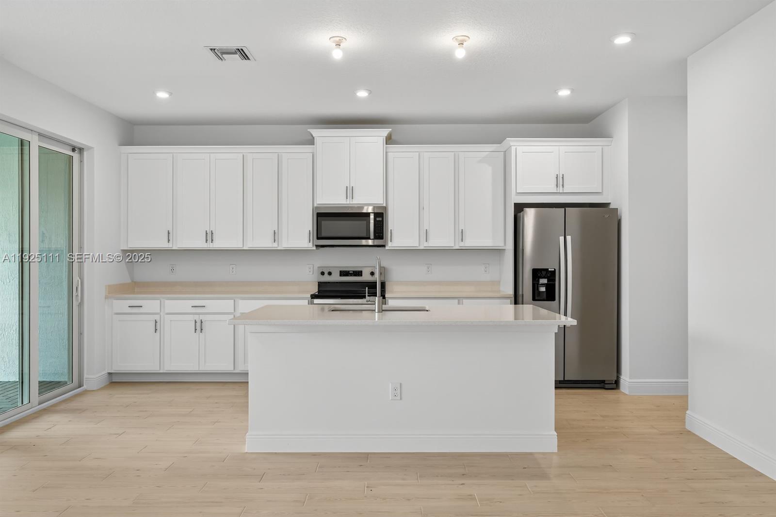 3585 Northwest Solange Court, Unit 3585 Jensen Beach, FL 34957 - Photo 12 of 33 a kitchen with kitchen island a white cabinets and refrigerator