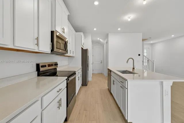 a kitchen with stainless steel appliances a sink stove top oven and white cabinets