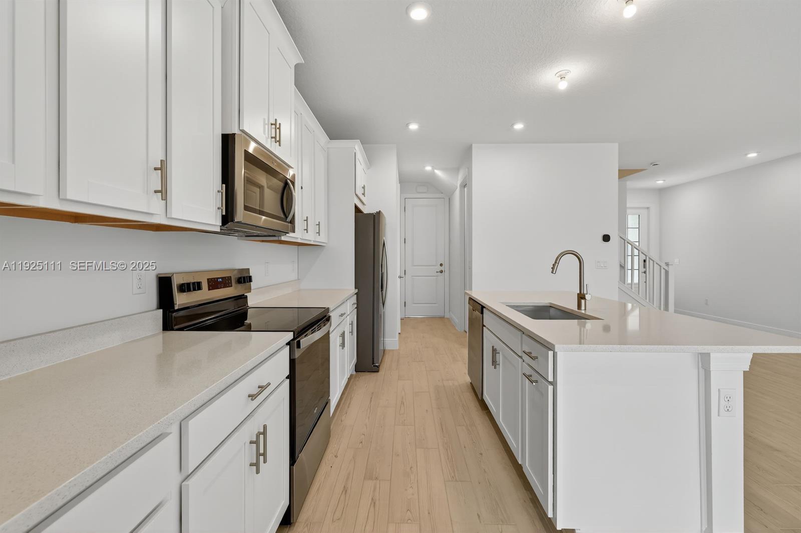3585 Northwest Solange Court, Unit 3585 Jensen Beach, FL 34957 - Photo 14 of 33 a kitchen with stainless steel appliances a sink stove top oven and white cabinets