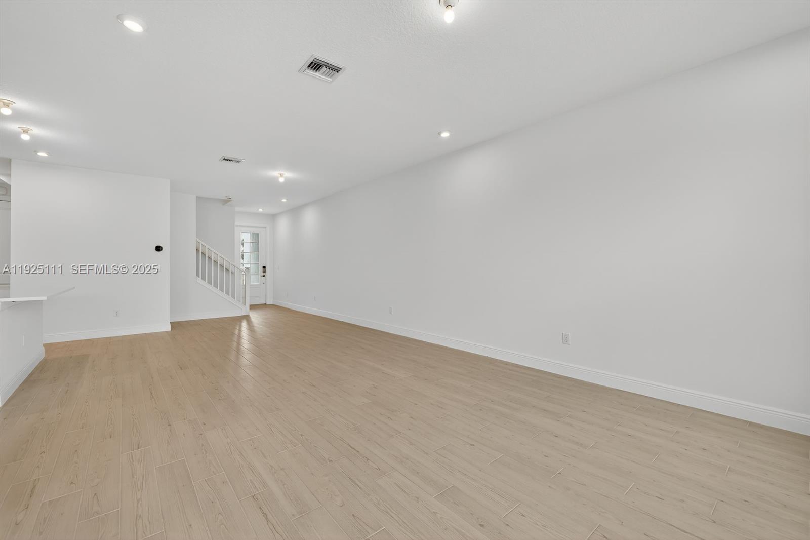 3585 Northwest Solange Court, Unit 3585 Jensen Beach, FL 34957 - Photo 9 of 33 an empty room with wooden floor and windows