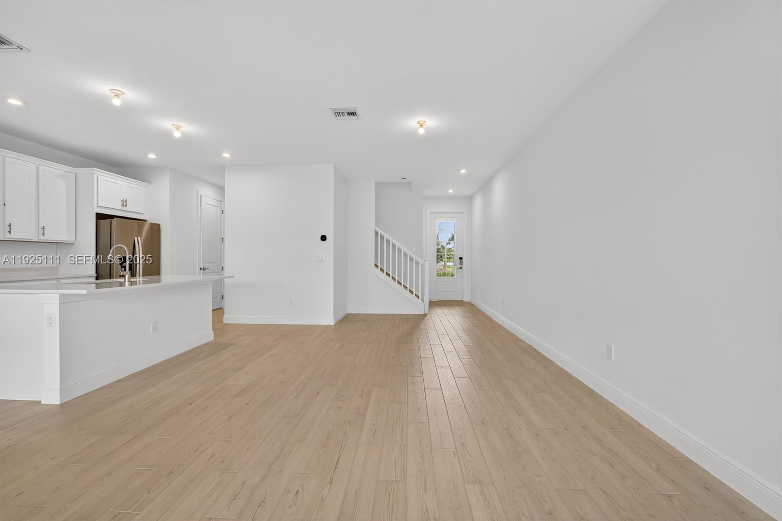 3585 Northwest Solange Court, Unit 3585 Jensen Beach, FL 34957 - Photo 10 of 33 a view of empty room with wooden floor and kitchen