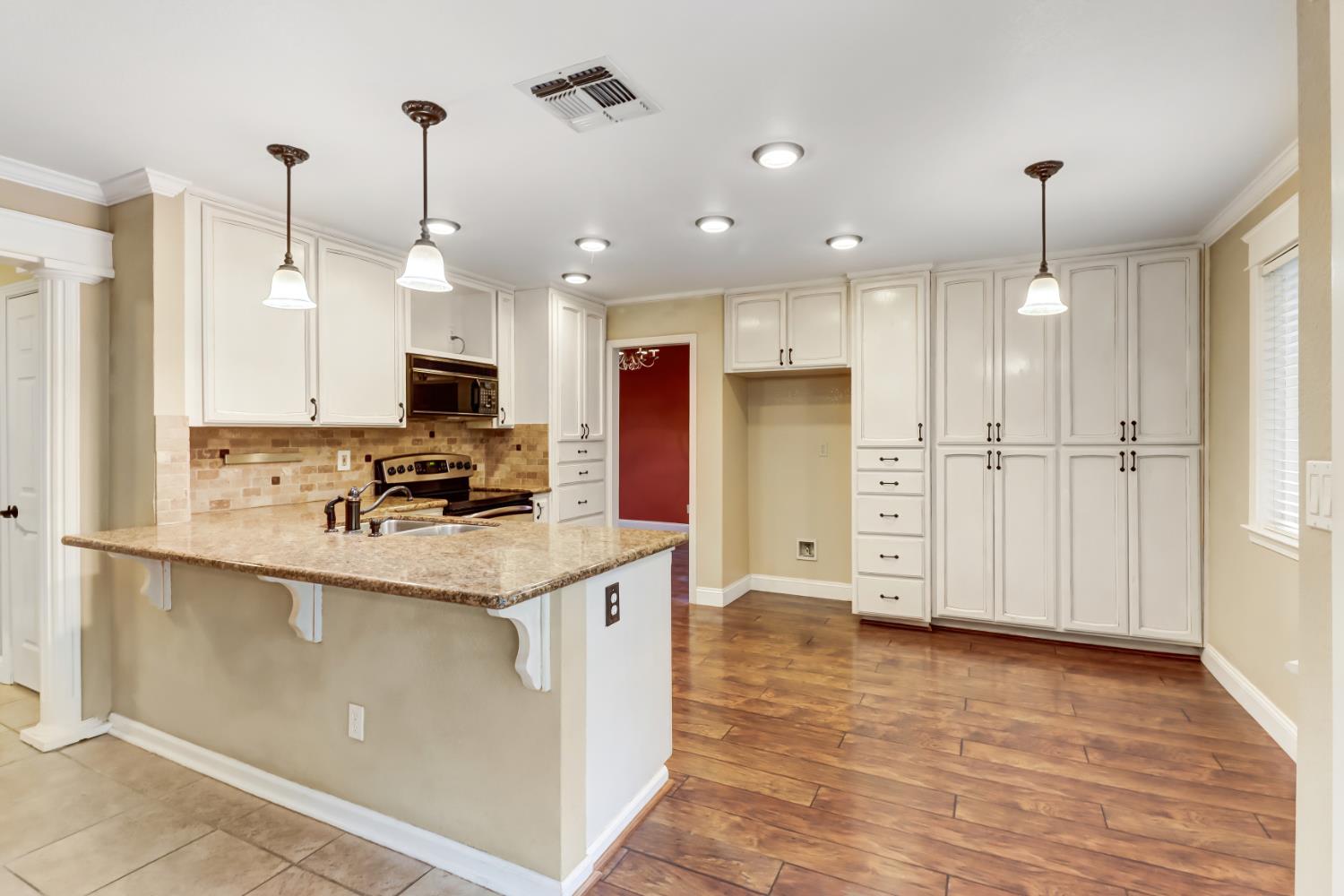 4683 Abrijo Road Cameron Park, CA 95682 - Photo 10 of 53 a kitchen with stainless steel appliances kitchen island granite countertop a stove a refrigerator a sink and white cabinets with wooden floor