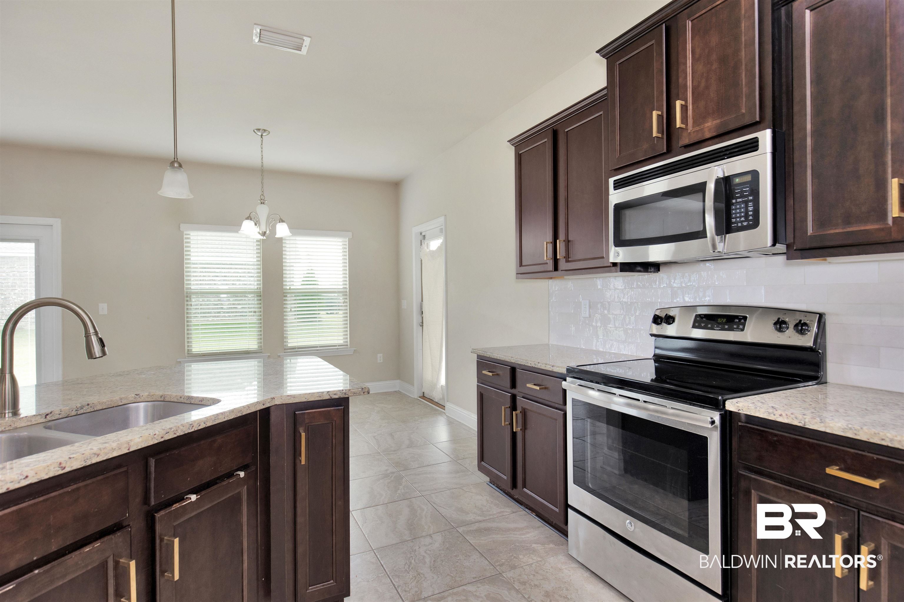122 Open Field Drive Fairhope, AL 36532 - Photo 9 of 27 Kitchen featuring a notable chandelier, stainless steel appliances, hanging light fixtures, decorative backsplash, and light tile patterned floors