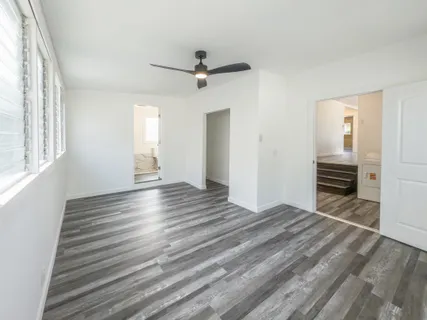 an empty room with wooden floor and windows