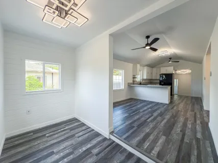 a view of kitchen and empty room with wooden floor