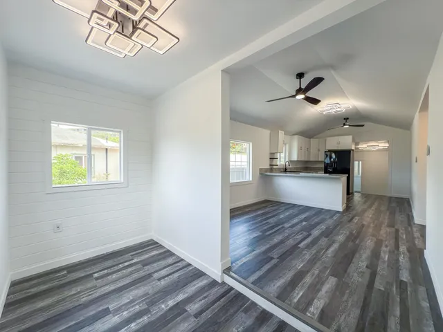 a view of kitchen and empty room with wooden floor