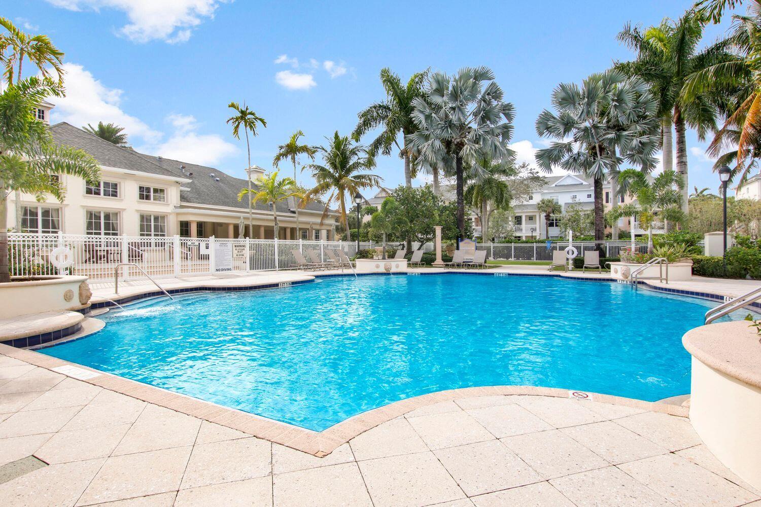 225 Murcia Drive, Unit 307 Jupiter, FL 33458 - Photo 36 of 36 a view of a swimming pool with a lawn chairs under palm trees