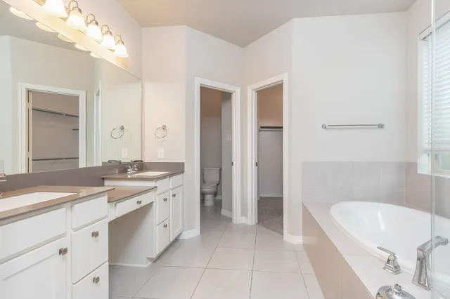 a spacious bathroom with a granite countertop sink a bathtub and a mirror