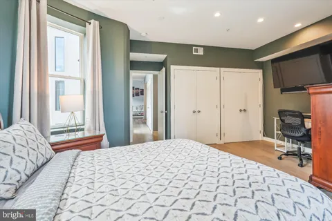 a bedroom with a large bed and a flat tv screen