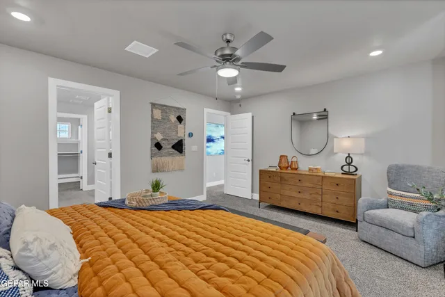 a bedroom with a bed large window couch and dresser