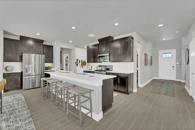 a large kitchen with cabinets chairs stainless steel appliances a sink and a counter top space