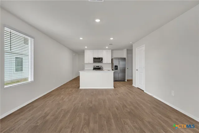 a view of a kitchen with a sink refrigerator and wooden floor