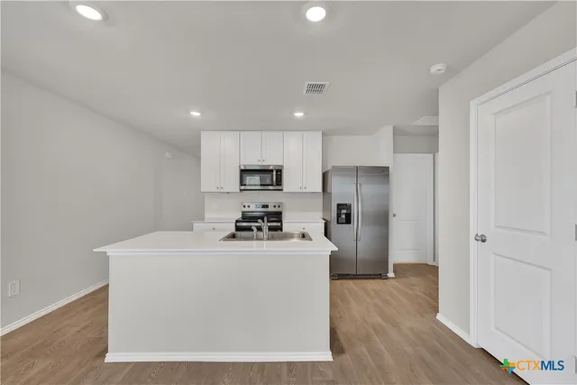 a kitchen with stainless steel appliances a refrigerator sink and wooden floor