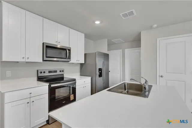 a kitchen with stainless steel appliances white cabinets and sink