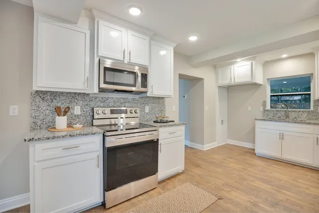 a kitchen with stainless steel appliances white cabinets and a stove a oven with white countertops