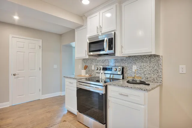 a kitchen with granite countertop white cabinets and a sink