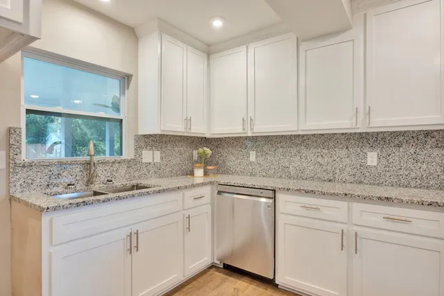 a kitchen with white cabinets and sink