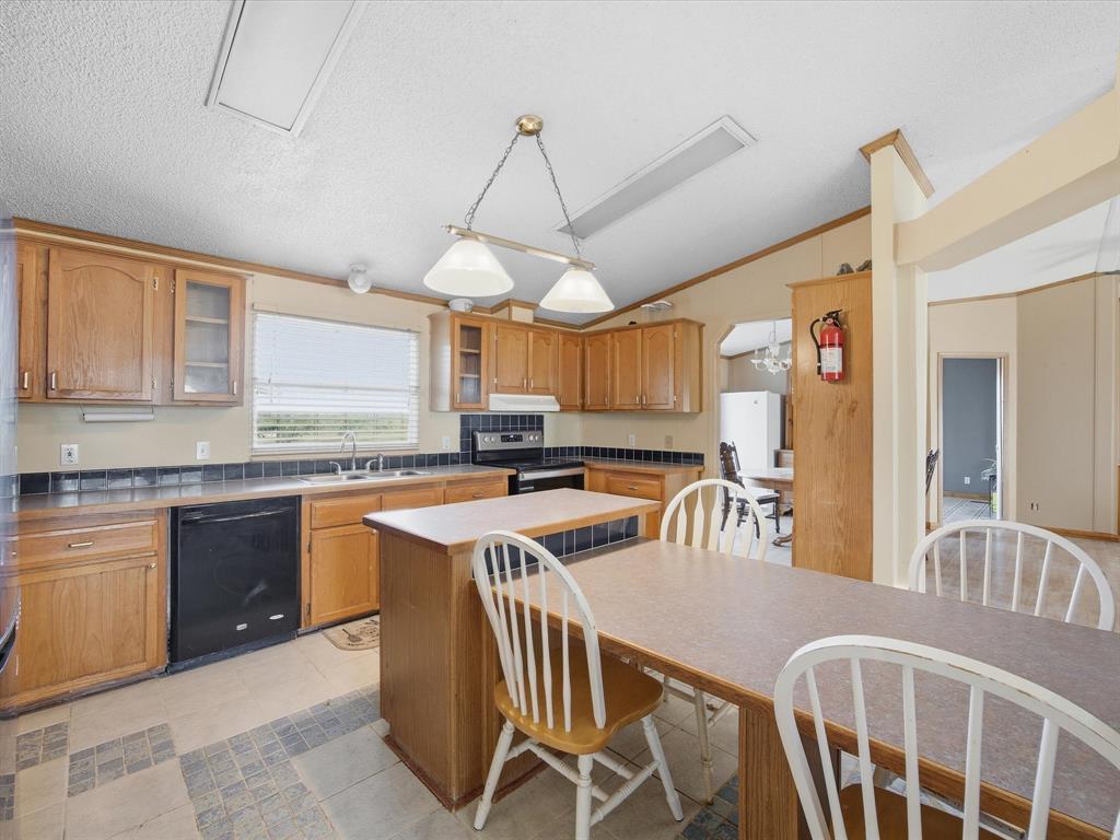 381 West McCool Road Nocona, TX 76255 - Photo 11 of 39 a kitchen with stainless steel appliances granite countertop a stove a sink dishwasher a dining table and chairs with wooden floor