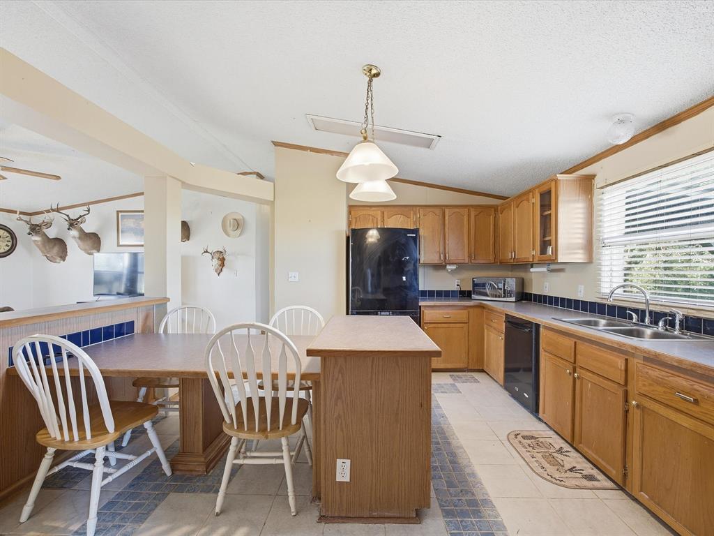 381 West McCool Road Nocona, TX 76255 - Photo 12 of 39 a large kitchen with cabinets chairs and refrigerator