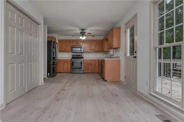 a large kitchen with cabinets wooden floor and stainless steel appliances