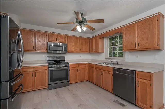 a kitchen with stainless steel appliances granite countertop a sink a stove a refrigerator cabinets and a refrigerator