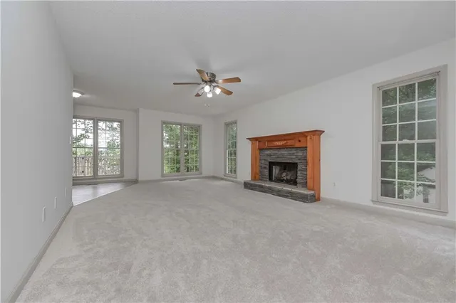 an empty room with windows and fireplace