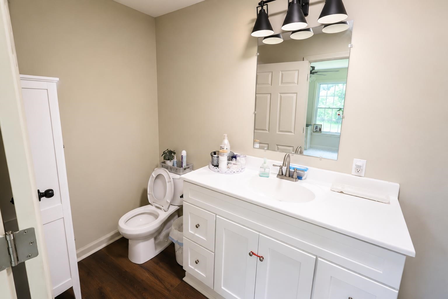 3226 19th Highway West Ripley, TN 38063 - Photo 15 of 18 Bright and functional bathroom featuring white cabinetry with ample storage, a spacious vanity with dual sink capabilities, and wood-finish flooring