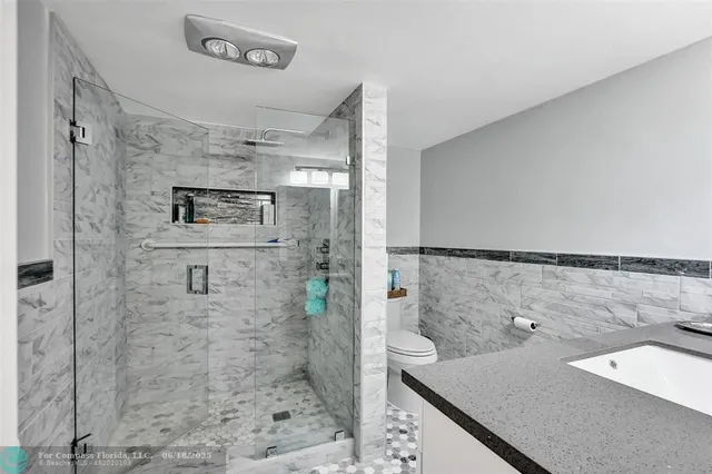 a bathroom with a granite countertop sink a toilet and shower
