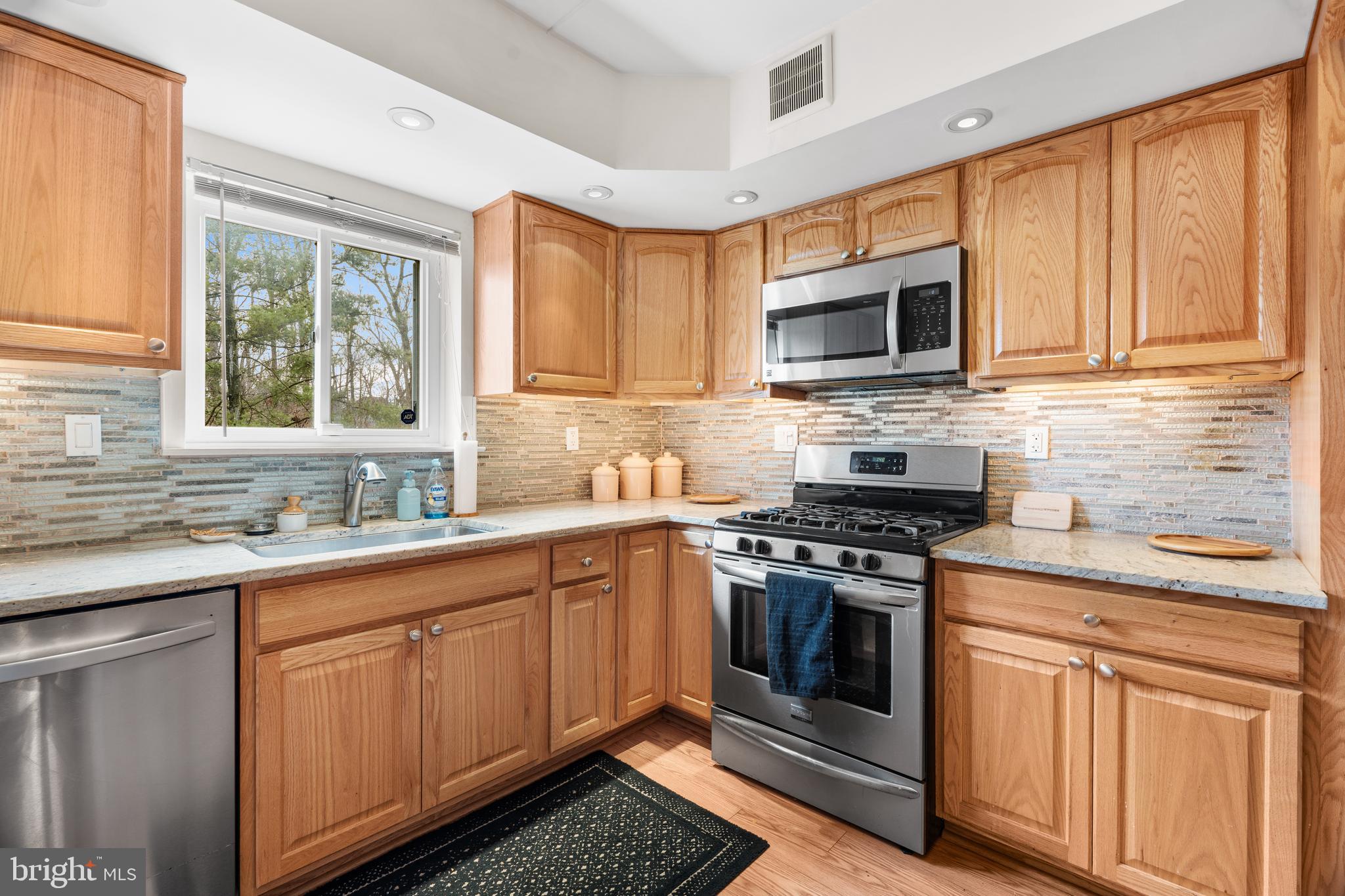 9945 Norwalk Road, Unit 15A Philadelphia, PA 19115 - Photo 11 of 23 a kitchen with stainless steel appliances granite countertop a stove sink microwave and cabinets