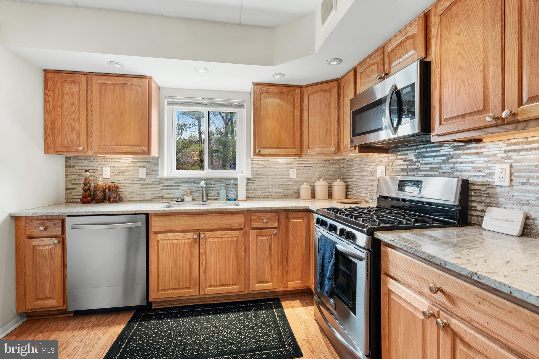 9945 Norwalk Road, Unit 15A Philadelphia, PA 19115 - Photo 9 of 23 a kitchen with stainless steel appliances granite countertop a stove a sink and a microwave