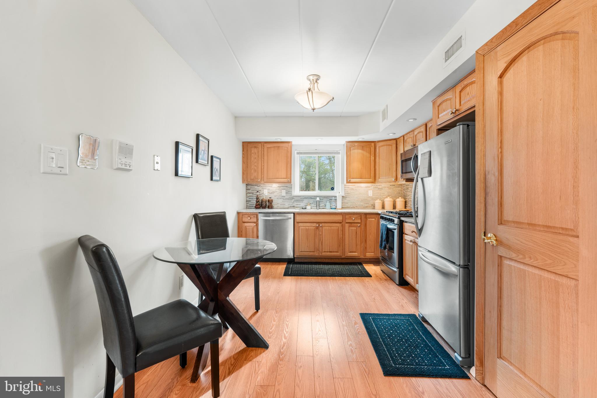 9945 Norwalk Road, Unit 15A Philadelphia, PA 19115 - Photo 10 of 23 a kitchen with a table chairs refrigerator and microwave