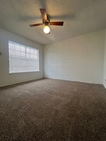 an empty room with windows and fan