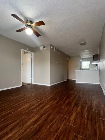 a view of empty room with wooden floor and fan