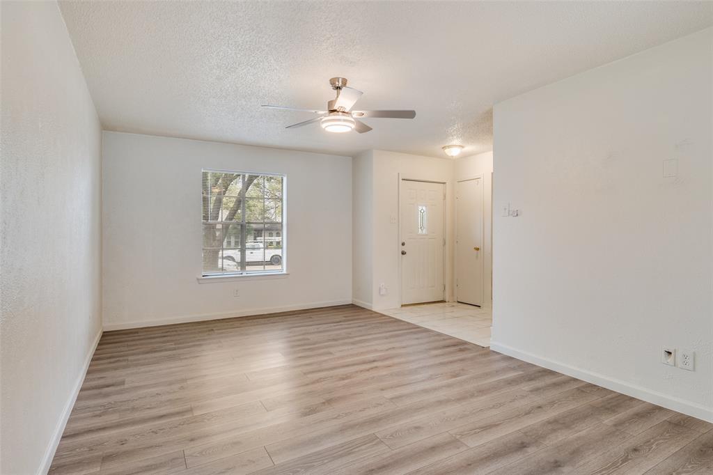 11348 McCree Road Dallas, TX 75238 - Photo 2 of 15 an empty room with wooden floor chandelier fan and windows