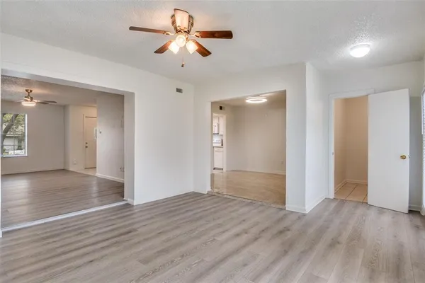 a view of empty room with wooden floor and ceiling fan